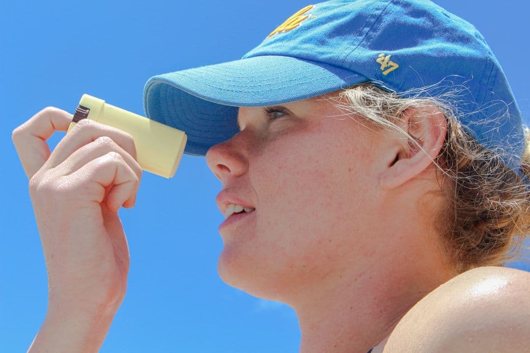 a woman wearing a blue hat looking through a magnifying glass